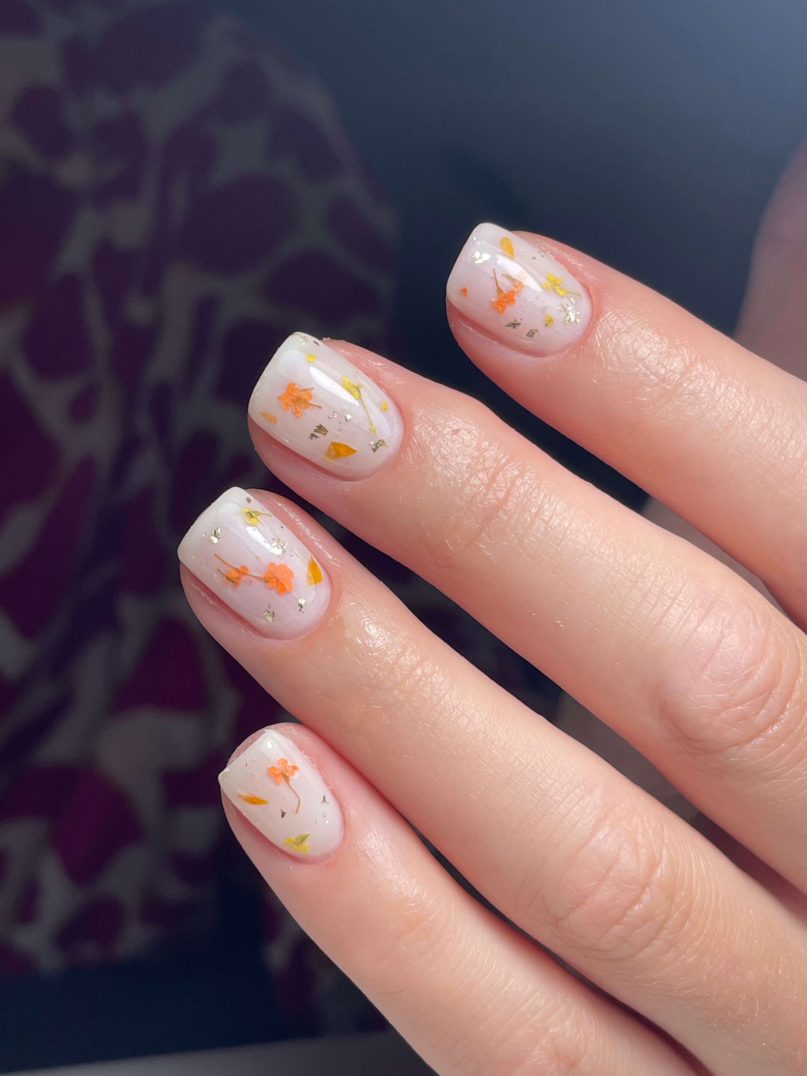 Nail art fleurs orange et jaune sur fond blanc ongles ovales courts