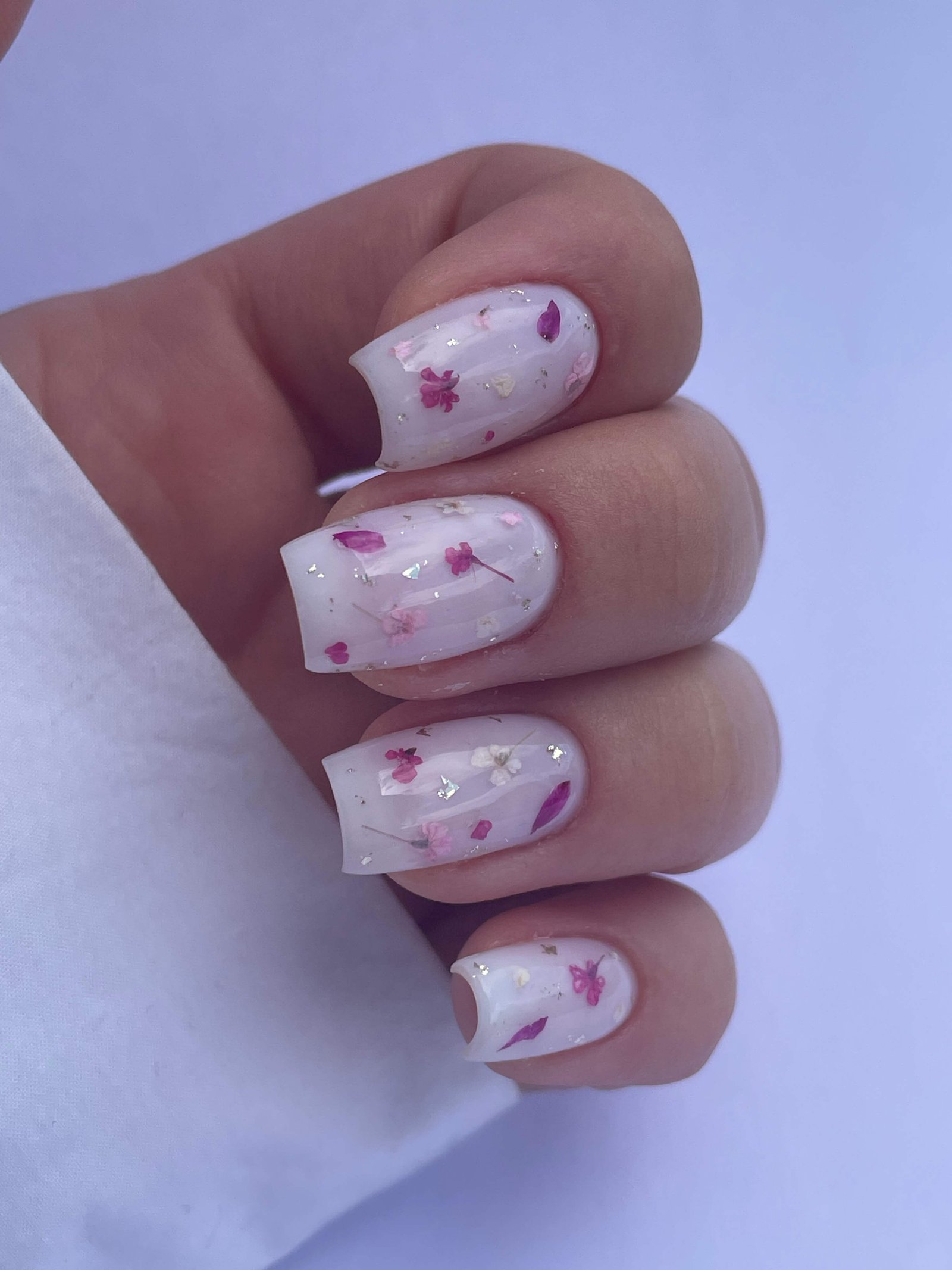 Nail art fleurs séchées roses incrustées sur fond blanc ongles carrés