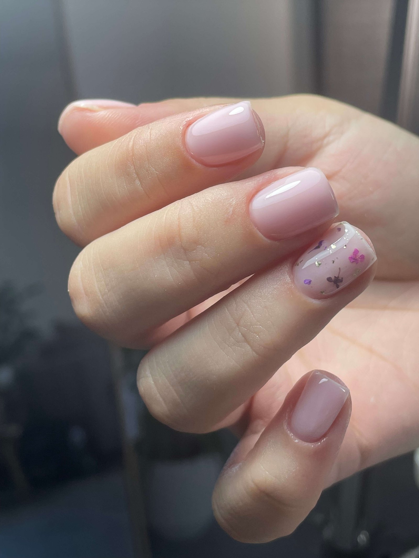 Manucure rose nude avec accent floral violet sur ongles ovales courts