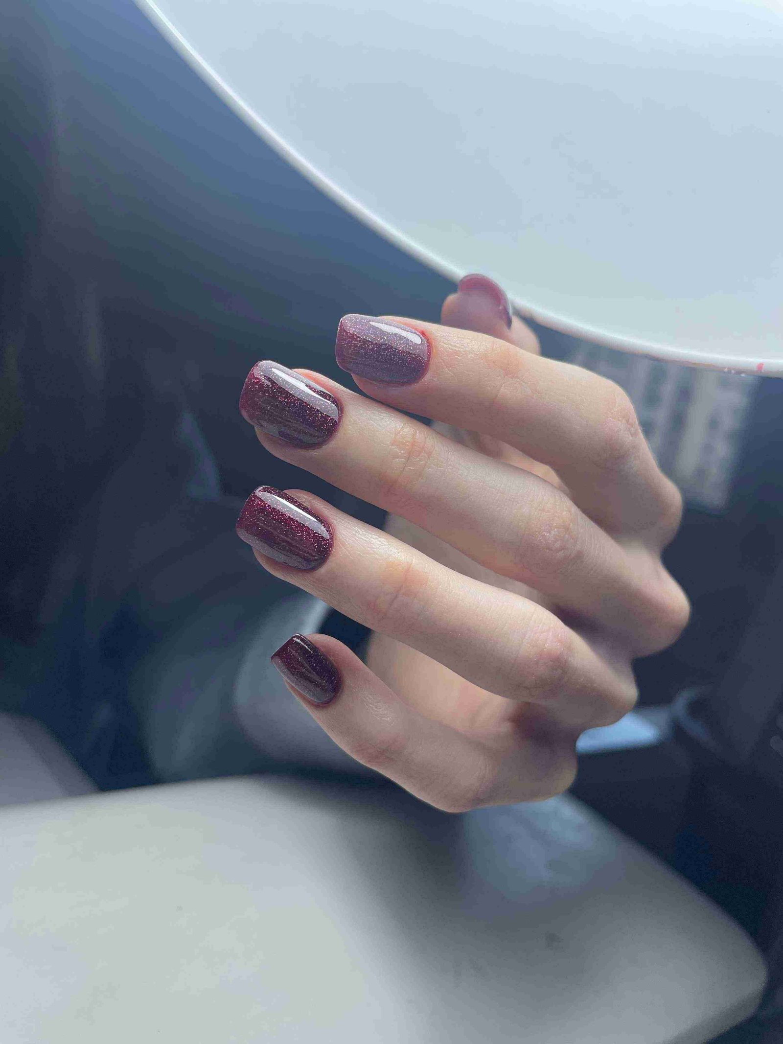 Vernis bordeaux avec paillettes dorées sur ongles ovales courts